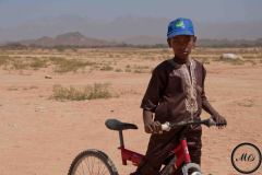 Un garçon se promène en bordure du festival de l'Aïr. Sur sa casquette, le logo d'Eucap Sahel; une mission civique de l'Union européenne, Iférouane, 2019.